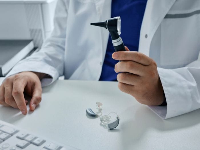 Audiologist holding otoscope in front of hearing aids