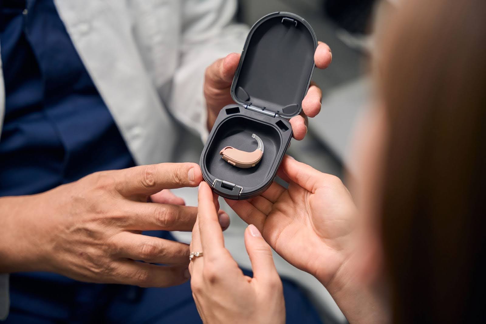 patient reaching towards the hearing aid in a case